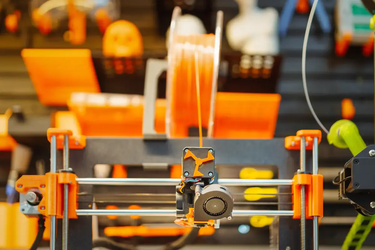 Tête d’une imprimante 3D à filament en cours d’impression, bobine en arrière-plan