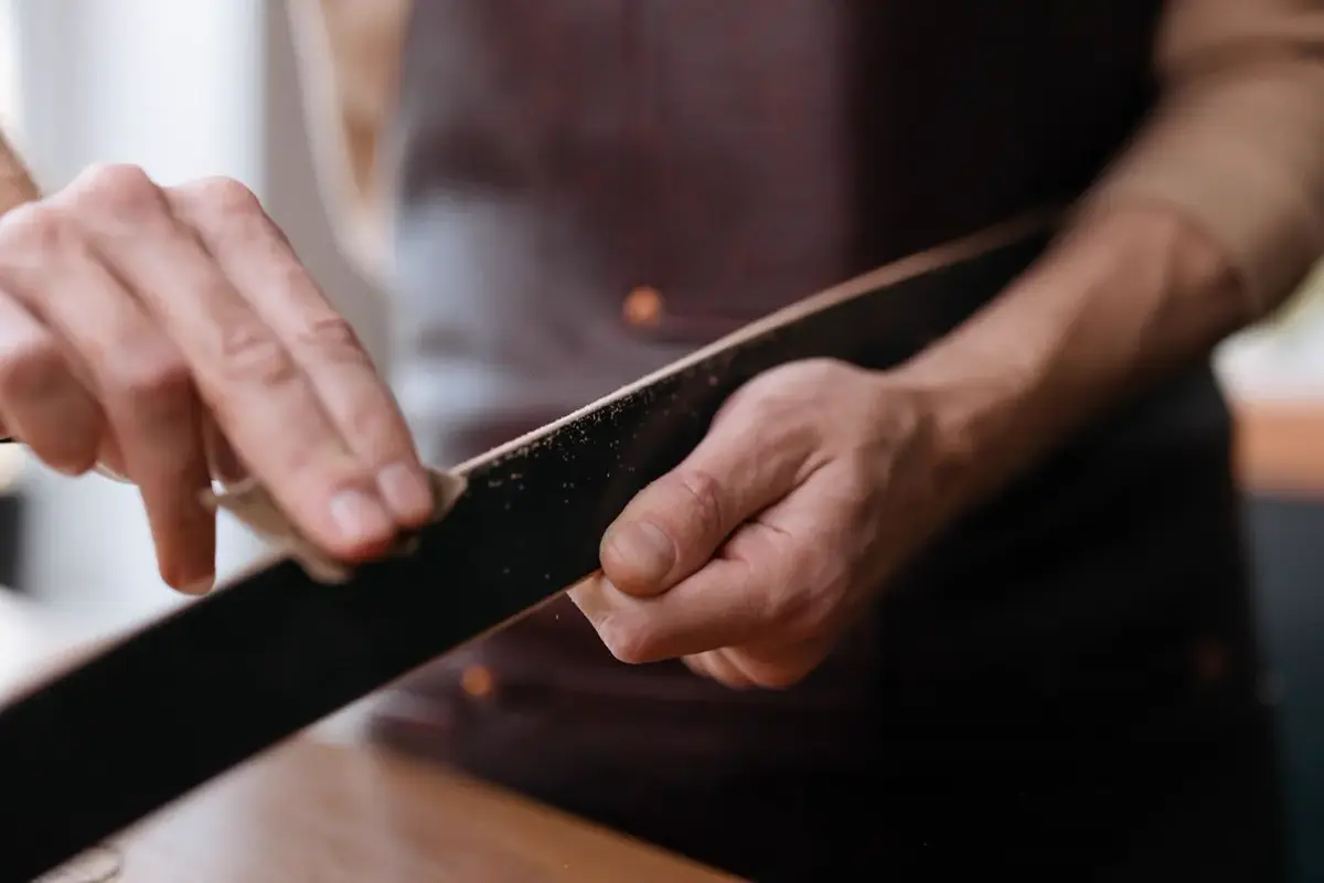 Mains qui poncent une longue pièce au papier abrasif